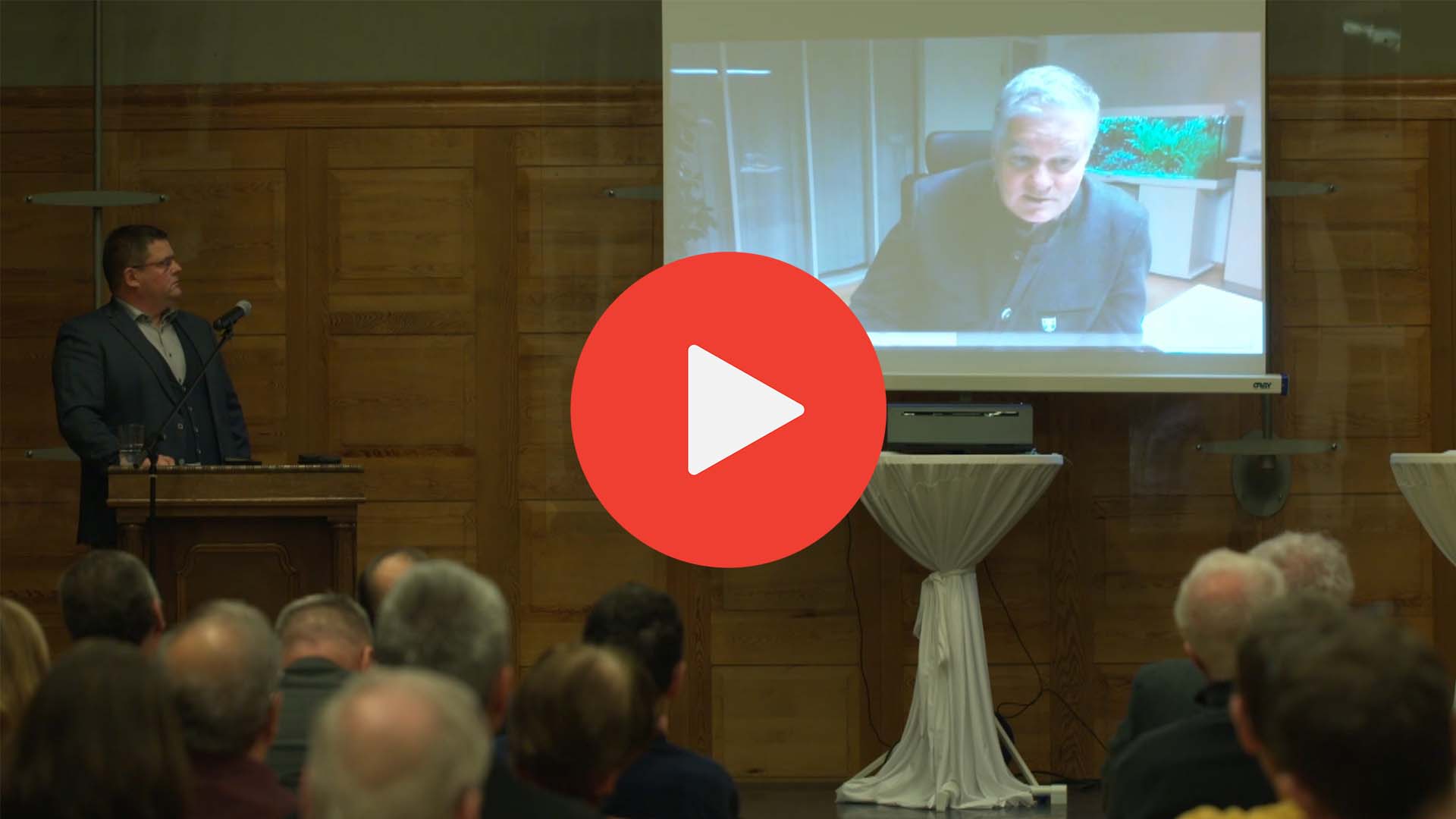 Oberbürgermeister Frank Höhme auf der Bühne und Garchings Erster Bürgermeister in Videobotschaft, Klick führt zu Youtube mit Aufzeichnung des Abends